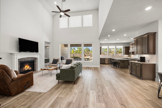 living room with a fireplace, light wood finished floors, recessed lighting, a ceiling fan, and baseboards