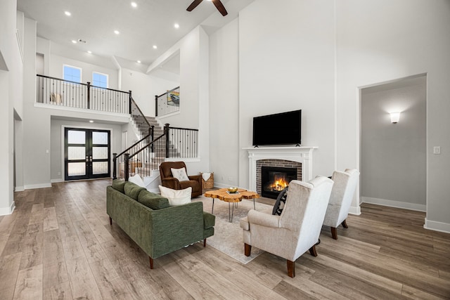 living area featuring french doors, a fireplace, light wood finished floors, plenty of natural light, and stairs