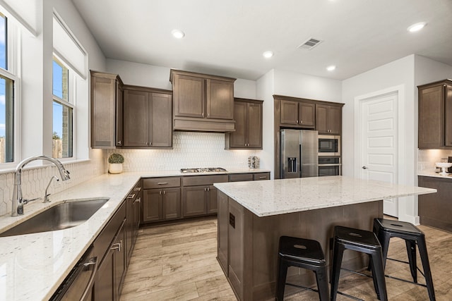 kitchen with light stone countertops, a breakfast bar area, appliances with stainless steel finishes, and a sink