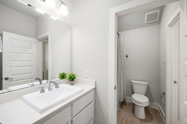 bathroom with toilet, a shower with shower curtain, vanity, visible vents, and baseboards