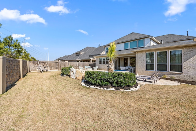 back of property featuring brick siding, a fenced backyard, a lawn, and a patio