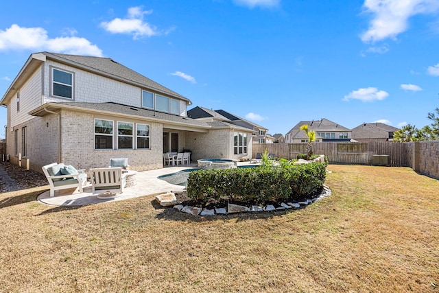 rear view of house with a fenced backyard, an in ground hot tub, a yard, a patio area, and brick siding