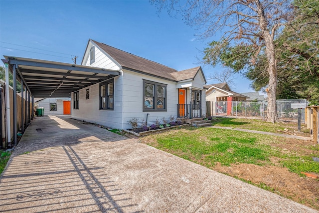 bungalow with an attached carport, driveway, a front lawn, and fence