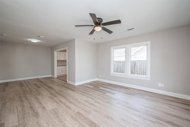 empty room with light wood-style floors, baseboards, visible vents, and ceiling fan