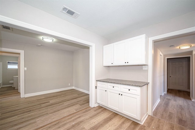 interior space featuring light wood-style flooring, visible vents, and white cabinetry