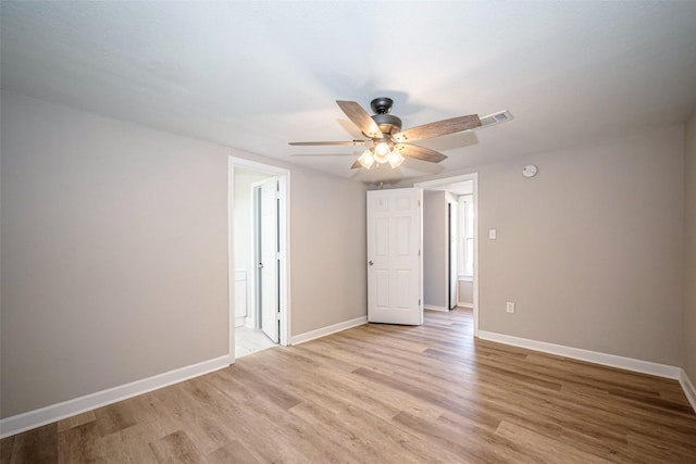 unfurnished room featuring light wood-style floors, visible vents, baseboards, and ceiling fan