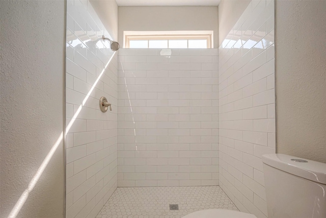 bathroom featuring a textured wall, a stall shower, and toilet