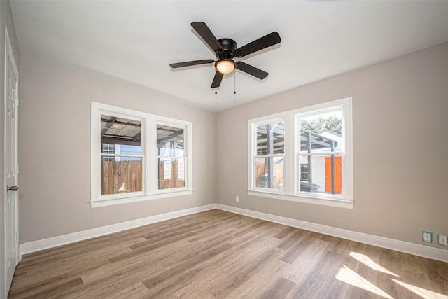 empty room with a ceiling fan, light wood-style flooring, and baseboards