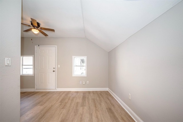 spare room featuring lofted ceiling, ceiling fan, light wood finished floors, and baseboards