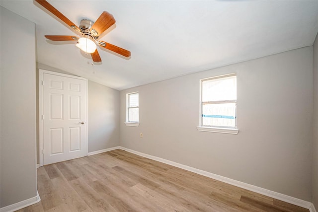 spare room featuring vaulted ceiling, light wood finished floors, a ceiling fan, and baseboards