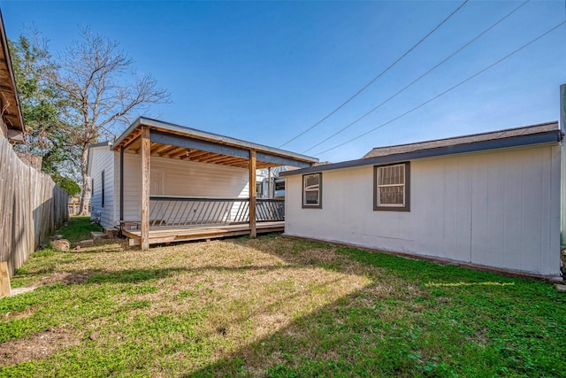 rear view of house featuring a deck, a lawn, and fence