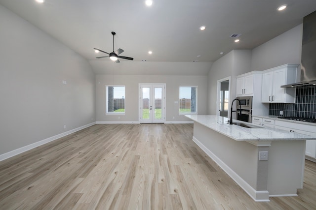 kitchen with stainless steel appliances, a spacious island, a sink, white cabinets, and french doors