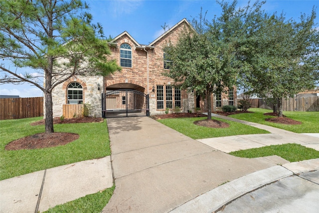 traditional-style house featuring driveway, a fenced front yard, a gate, a front lawn, and brick siding