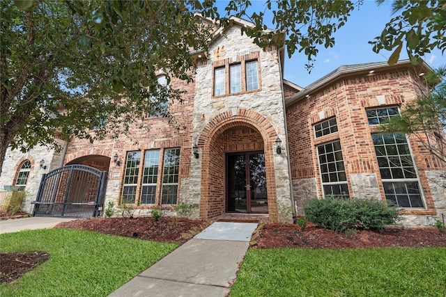 view of front of house with stone siding, a gate, a front lawn, and brick siding