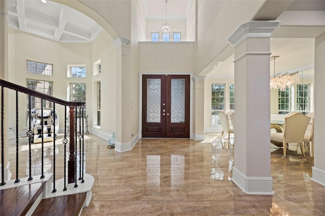 foyer entrance featuring decorative columns, baseboards, coffered ceiling, marble finish floor, and a chandelier