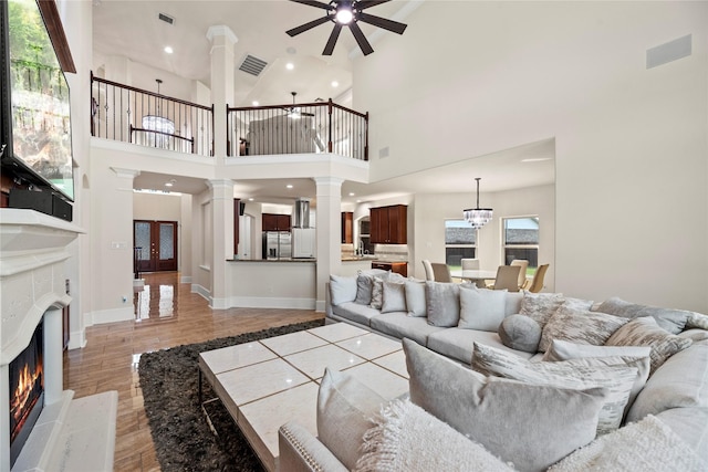 living area featuring a fireplace, decorative columns, visible vents, and wood finished floors