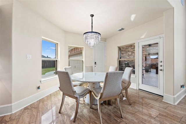 dining room featuring baseboards, light wood-type flooring, visible vents, and an inviting chandelier