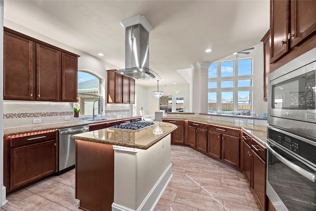 kitchen featuring light stone counters, a center island, stainless steel appliances, island range hood, and a peninsula