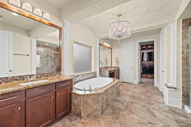 full bathroom featuring decorative columns, a sink, a walk in closet, a shower stall, and two vanities