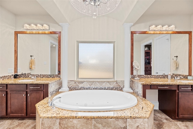 bathroom featuring two vanities, a garden tub, decorative columns, and a sink