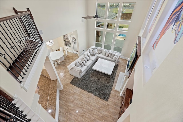 living room with baseboards, a high ceiling, stairway, and a ceiling fan