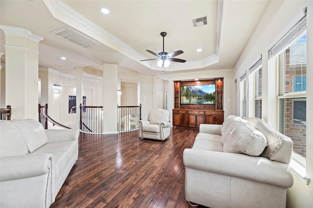 living area with dark wood-style floors, a raised ceiling, visible vents, and ornamental molding