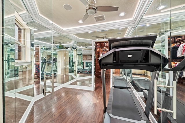 exercise room with ceiling fan, visible vents, crown molding, and wood finished floors