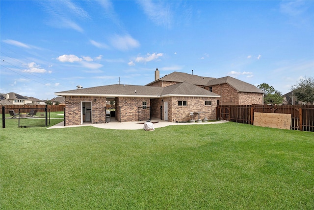 back of property with a patio area, a lawn, and a fenced backyard