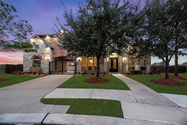 view of front of property featuring stone siding, a fenced front yard, and a gate