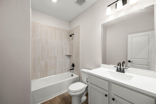 bathroom featuring visible vents, toilet, wood finished floors, vanity, and washtub / shower combination