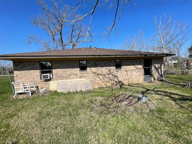 back of house featuring a yard, brick siding, a shingled roof, and cooling unit