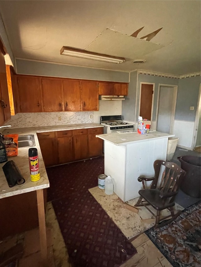 kitchen with brown cabinets, white range with gas stovetop, and light countertops