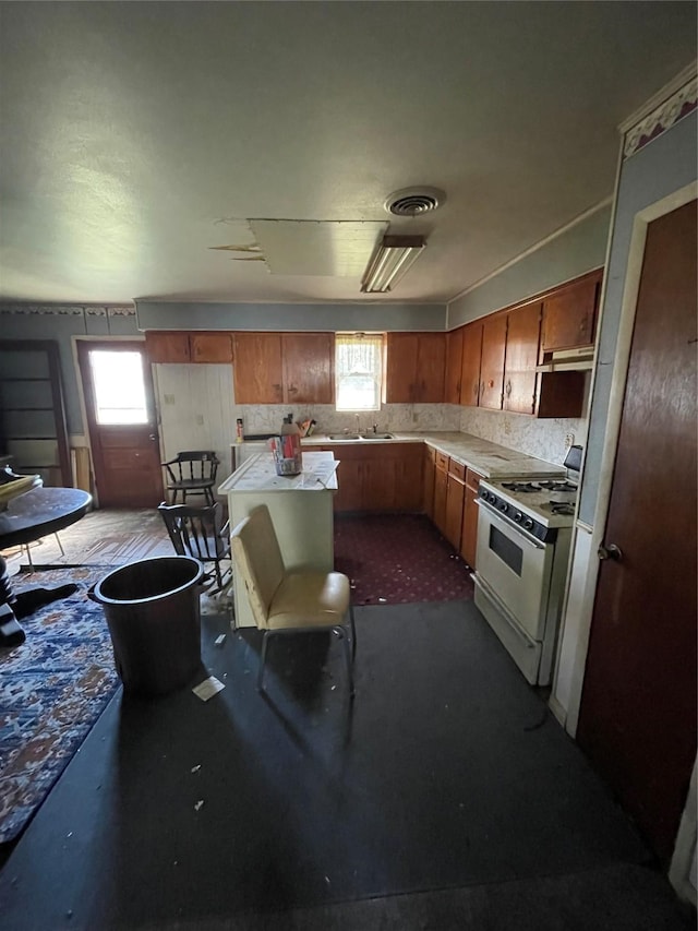 kitchen with white range with gas cooktop, visible vents, light countertops, and a wealth of natural light