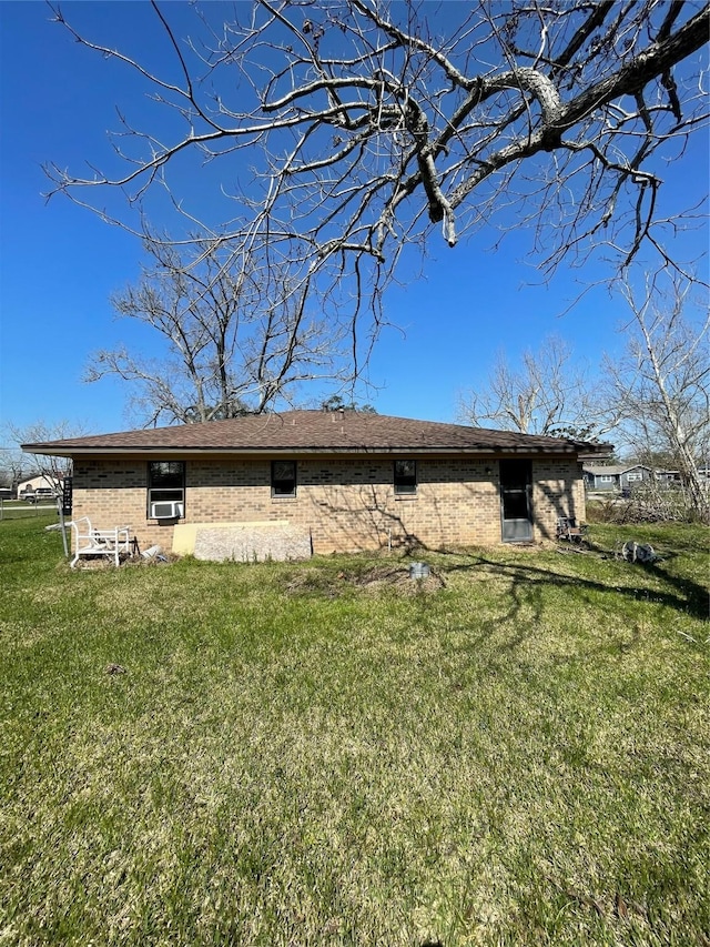 rear view of property with a lawn and brick siding