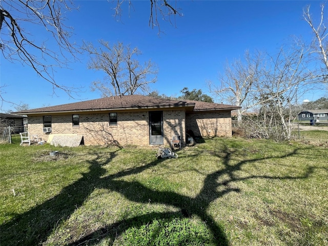 rear view of house featuring brick siding, fence, and a yard