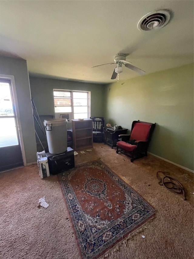 sitting room with carpet floors, a ceiling fan, visible vents, and baseboards