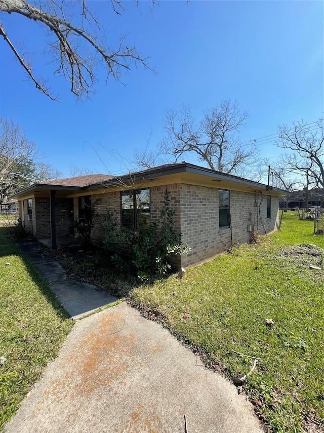 view of side of property featuring brick siding and a yard