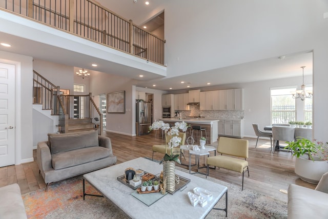 living room with baseboards, light wood-style flooring, stairs, a chandelier, and recessed lighting