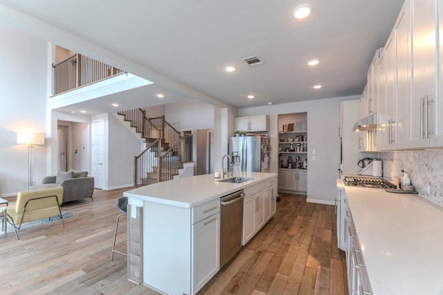 kitchen with stainless steel appliances, white cabinets, light countertops, and under cabinet range hood