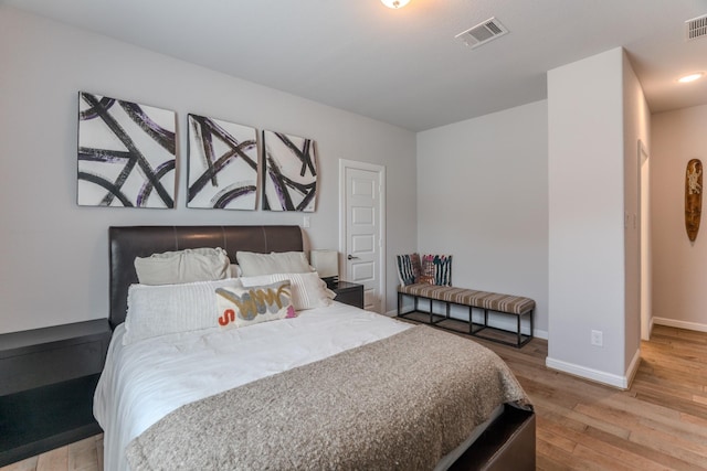 bedroom featuring baseboards, visible vents, and wood finished floors