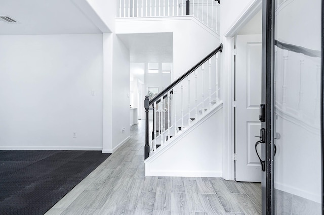 entryway with light wood-type flooring, stairway, baseboards, and visible vents