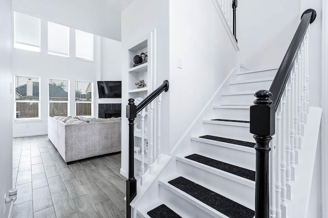 stairs with built in features, a fireplace, baseboards, and wood finished floors