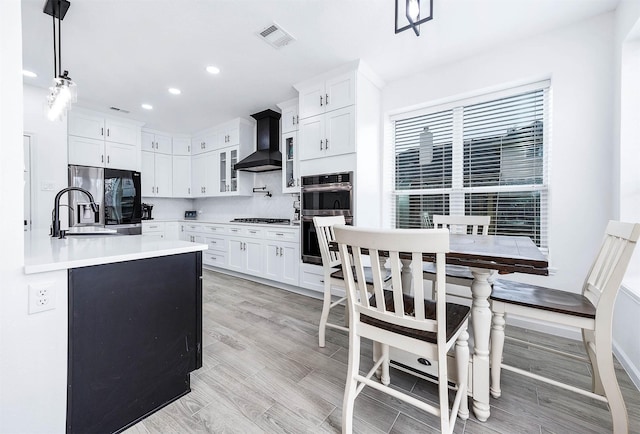 kitchen featuring white cabinets, hanging light fixtures, light countertops, stainless steel appliances, and premium range hood