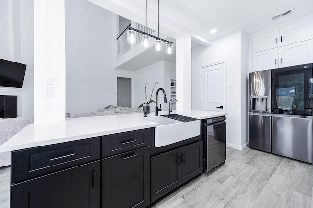 kitchen with black dishwasher, light countertops, visible vents, open floor plan, and a sink