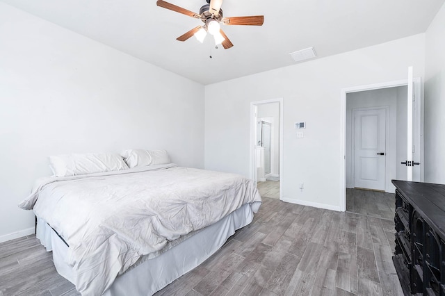 bedroom featuring ensuite bathroom, ceiling fan, baseboards, and wood finished floors