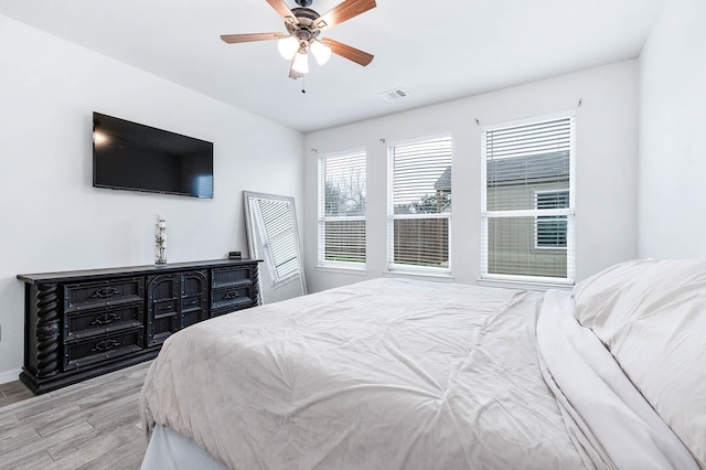 bedroom featuring light wood-style flooring, visible vents, and a ceiling fan