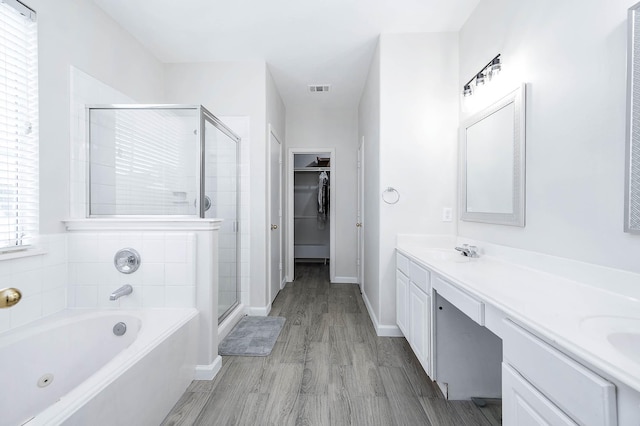 bathroom featuring a sink, a shower stall, a whirlpool tub, double vanity, and a walk in closet