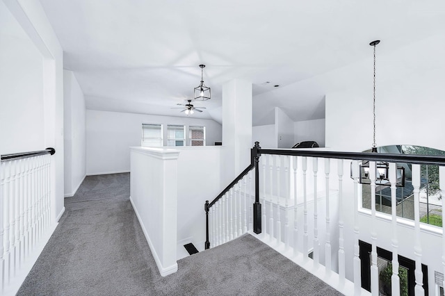 hallway featuring carpet, baseboards, vaulted ceiling, and an upstairs landing