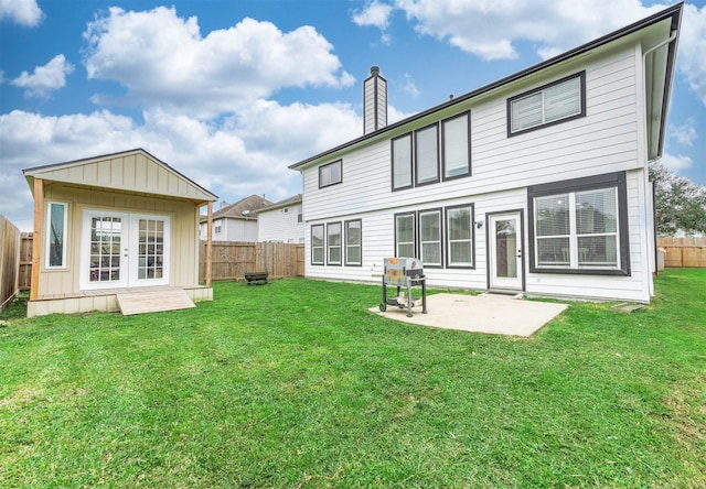 rear view of property featuring a yard, french doors, a patio area, and a fenced backyard