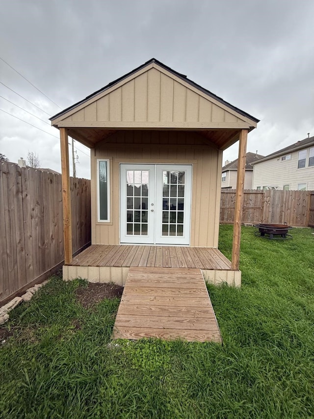 back of property featuring a yard, a fenced backyard, an outdoor fire pit, and an outdoor structure